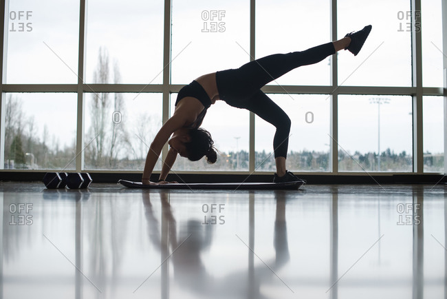 Landscape shot of a young dancer stretching on a yoga mat on the gym floor