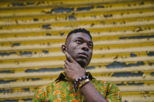 Horizontal portrait of a man posing in a colorful shirt in front of a storefront