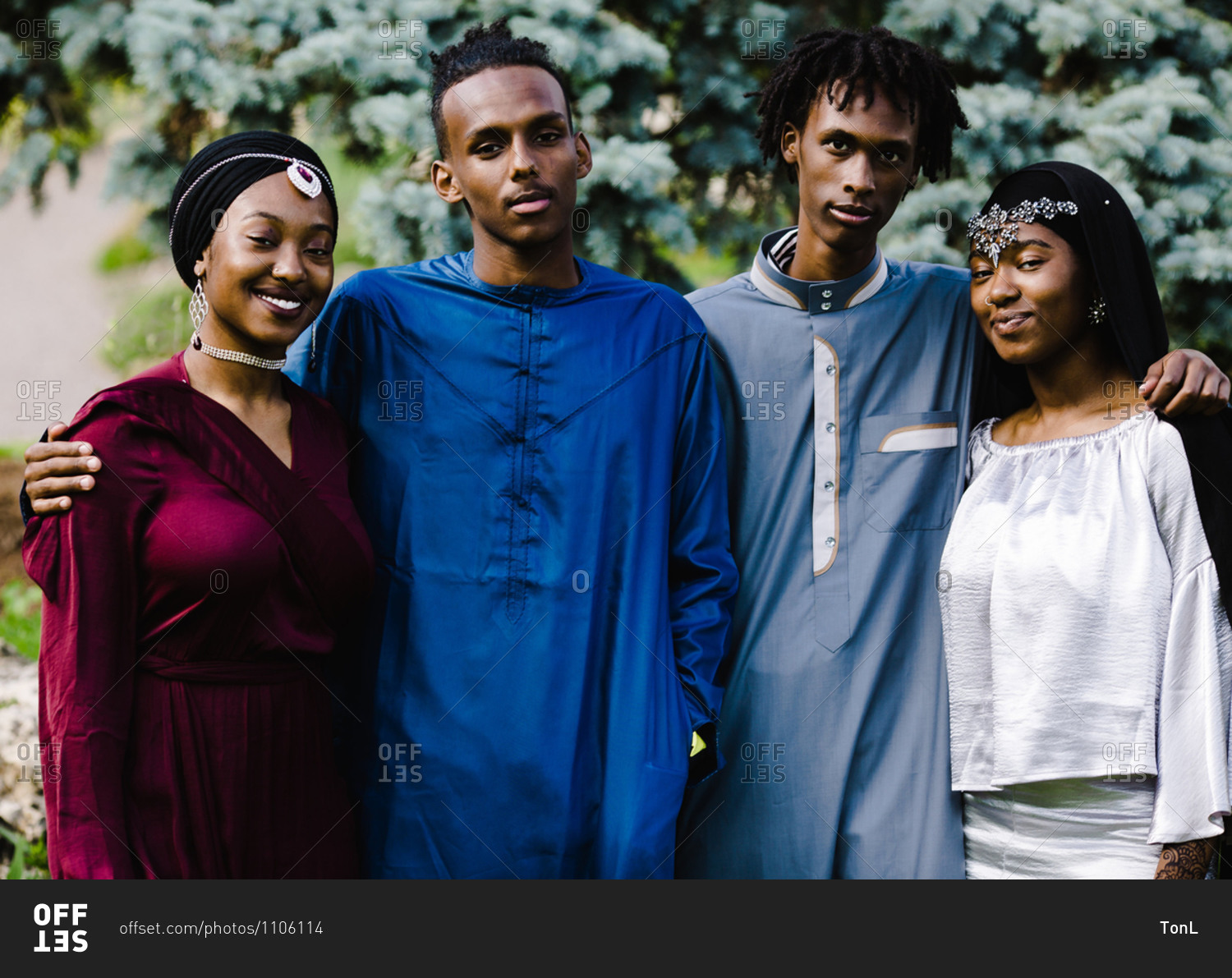 Two young black Muslim men standing with two black Muslim women in Islamic clothing