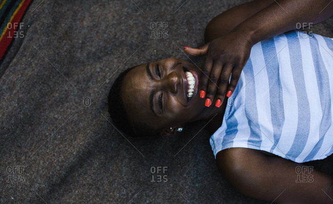 Happy black woman with red manicure lying down stock photo - OFFSET