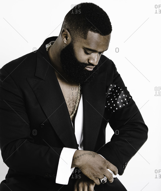 Portrait of a man with a beard dressed in a black jacket looking at his wrist watch