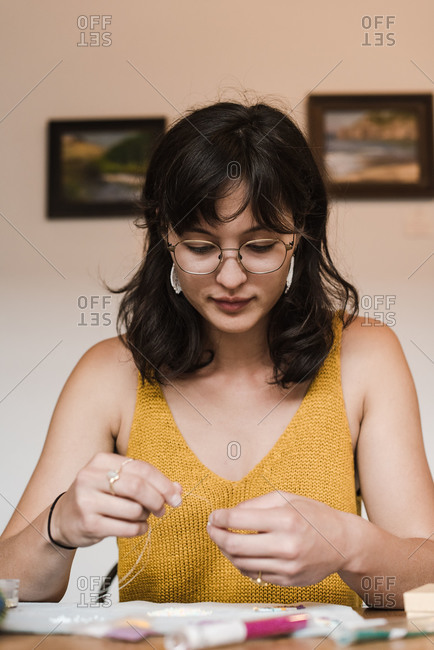 Vertical closeup of a young mixed race businesswoman making her own jewelry at home