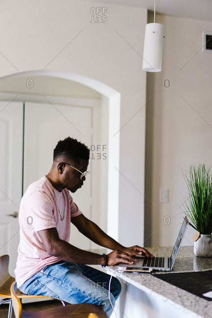 Side view of a man working on laptop on a counter