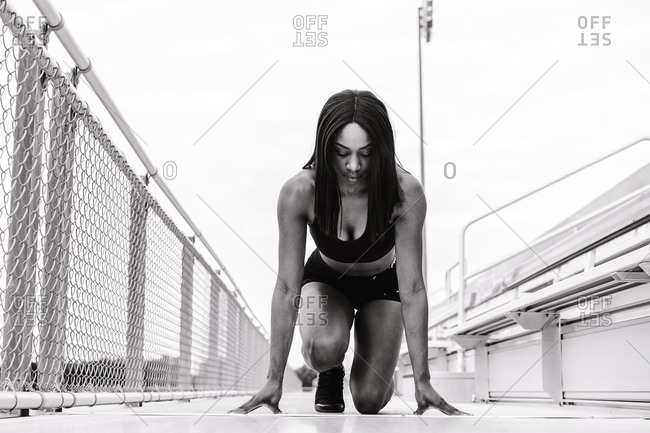Black and white shot of a black female athlete on mark on a race track