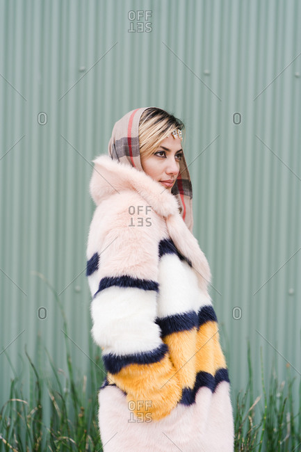 Vertical portrait of a Muslim woman posing with her hands in the pockets of her fur coat
