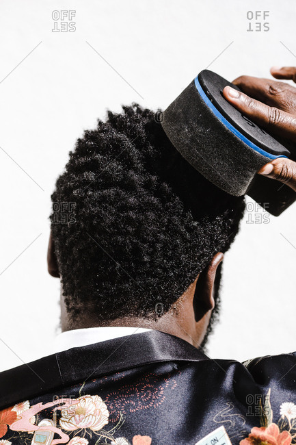 A close up shot from behind of a black man while he brushes his hair
