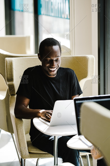 A young black man smiling at laptop