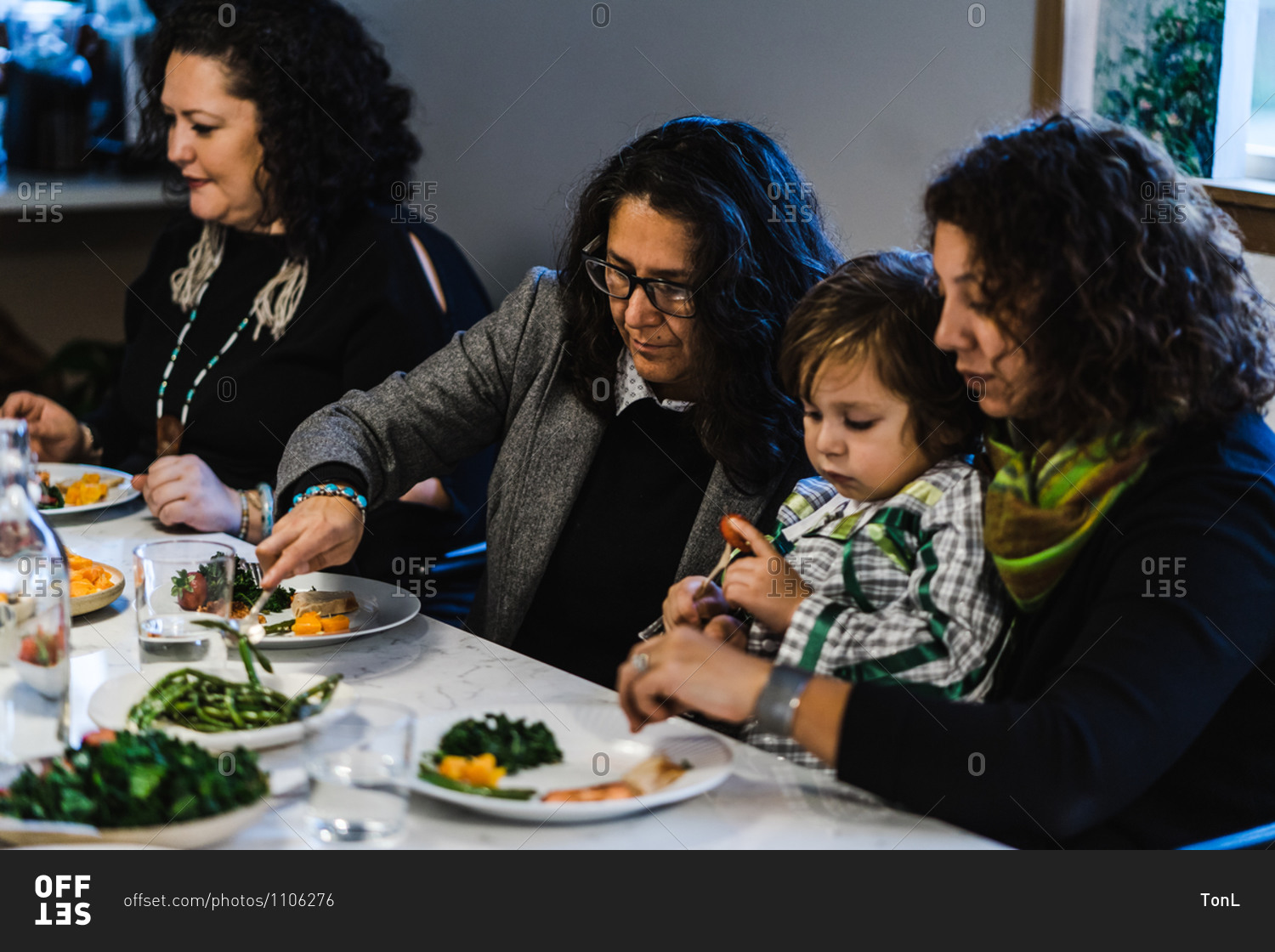 Horizontal shot of seated native american women dishing out food at a family meal