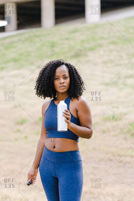Strong focused woman standing and drinking water
