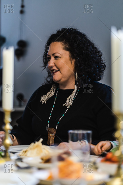 Vertical waist up portrait of a joyous woman with her family at the dinner table for a meal