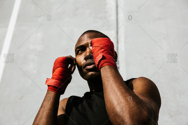 Low angle shot of a black boxer holding a stance with his hands covered in boxing wraps