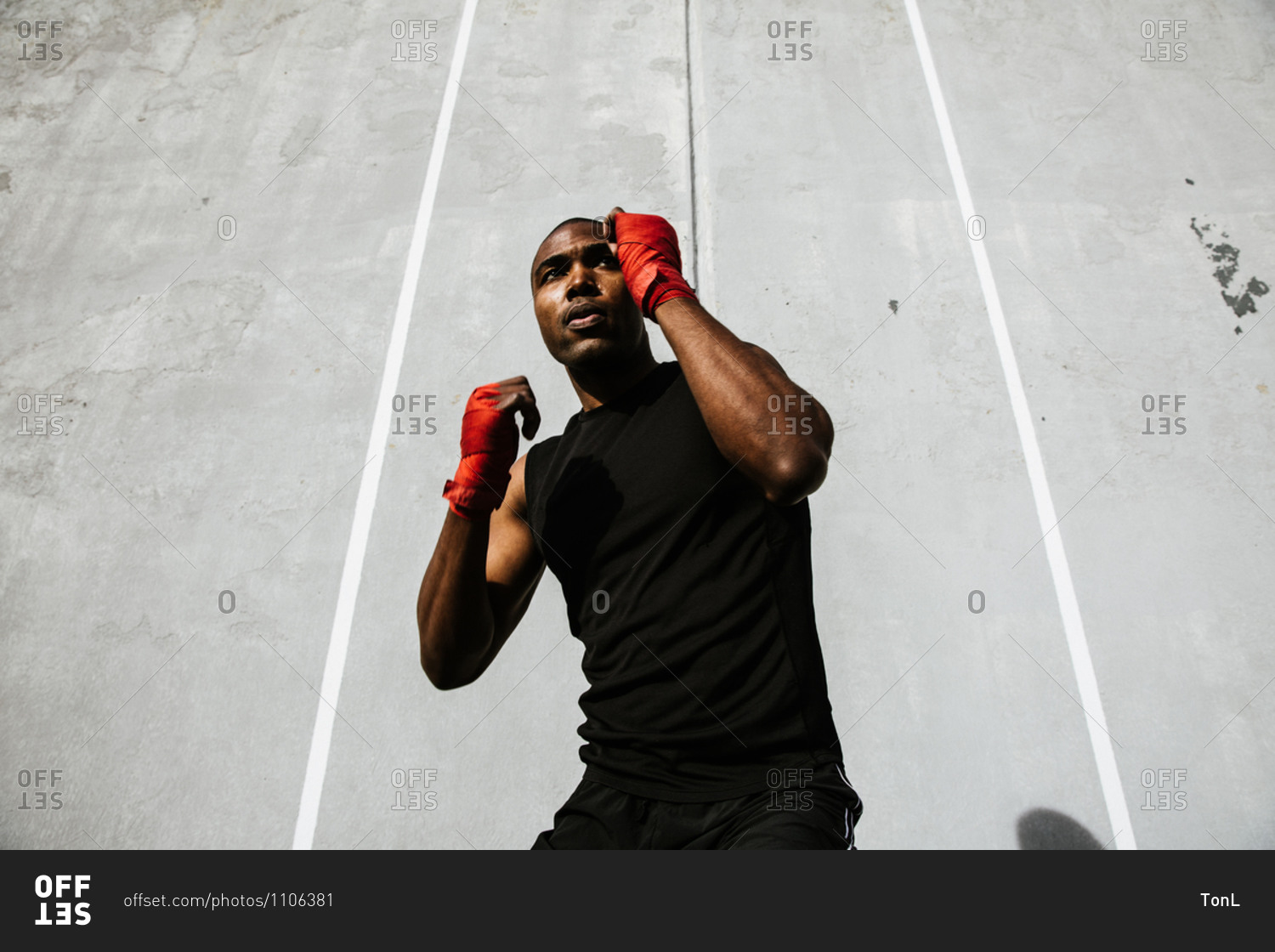 Fit black man in a boxing stance with his hands covered in boxing wraps