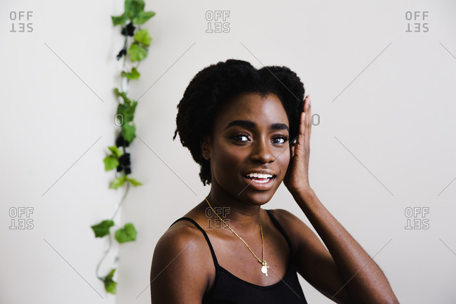 Portrait of a black model posing in front of a white wall and looking at the camera