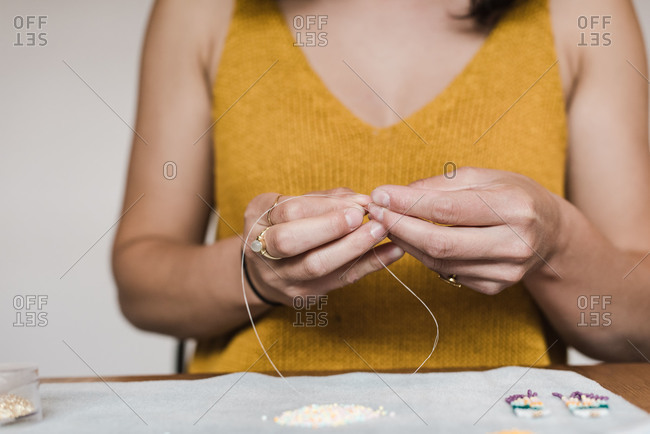 Horizontal close up on the hands of a mixed race woman making her own jewelry at home