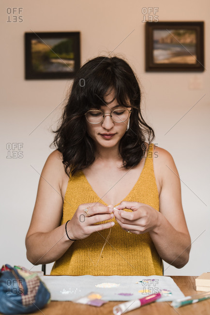 Vertical shot of a young mixed race businesswoman making her own jewelry at home