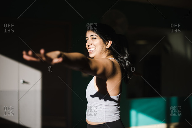 Happy smiling woman performing yoga in gym attire