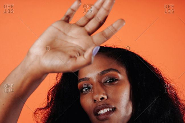Headshot of an attractive black, Ethiopian woman posing against an orange backdrop