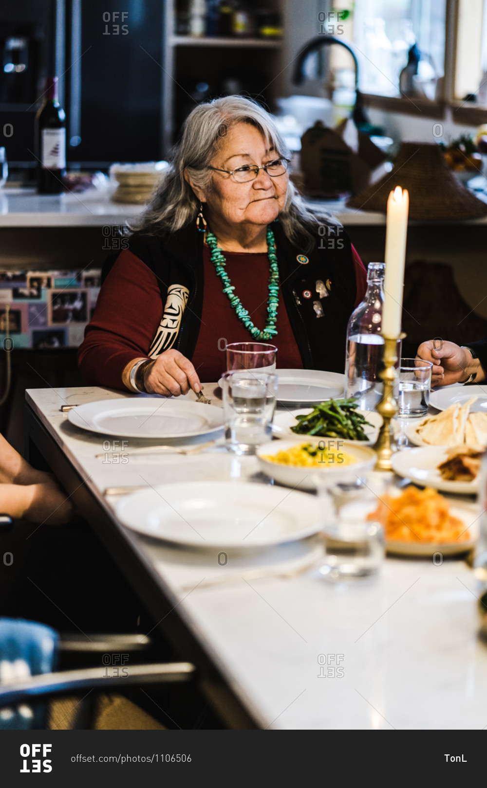 Vertical shot of a joyous american Indian and alaska native elder sitting at the head of the dinner table for a meal