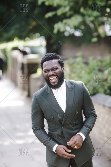 A portrait shot of an african american man laughing hard in a green suit
