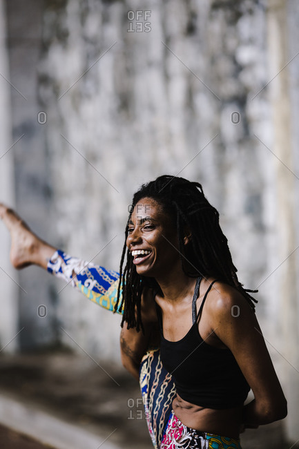 Black woman smiling while stretching out her leg in a yoga pose