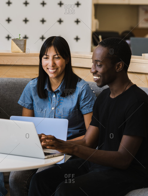 A portrait shot of a woman and a black man working on their laptops during a business meeting