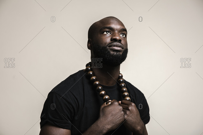 a grown man in a black leather suit and chain necklace posing very