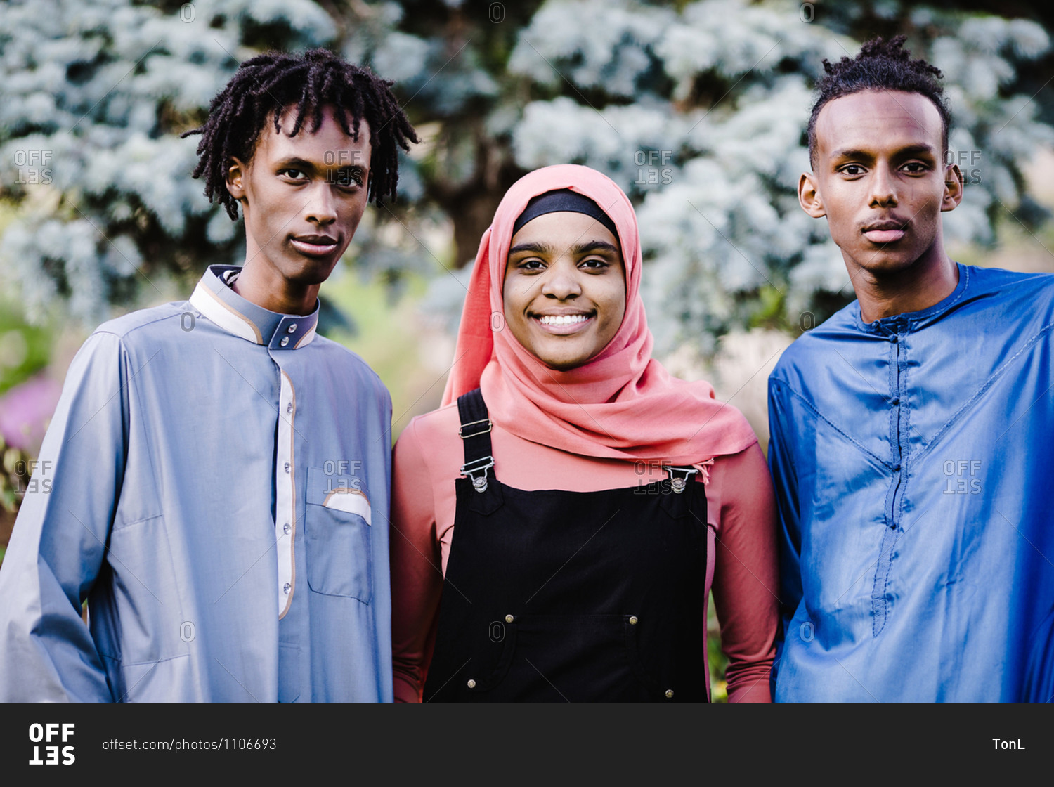 Young black Muslim men standing with a black Muslim woman in Islamic clothing