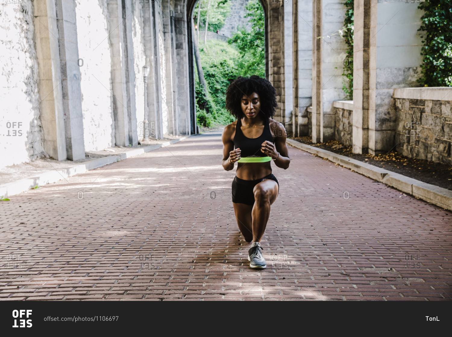 Black woman in athletic apparel exercising outdoors during daytime