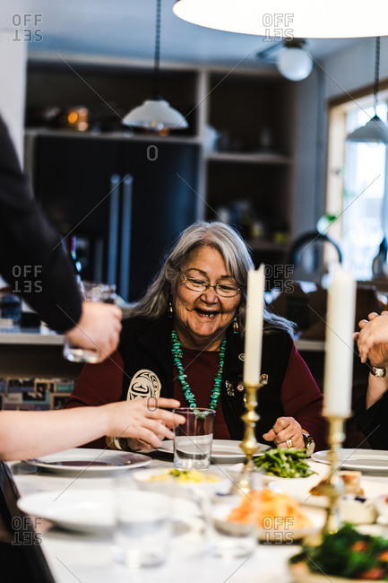 Horizontal shot of a grandmother laughing at the dinner table during a meal indoors