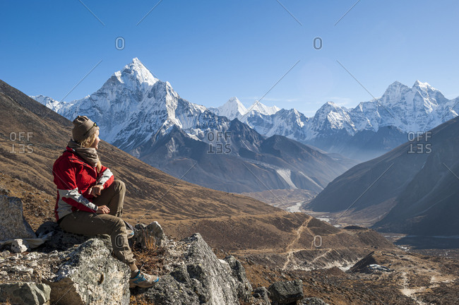 A trekker sits and admires views of Ama Dablam in the Everest region