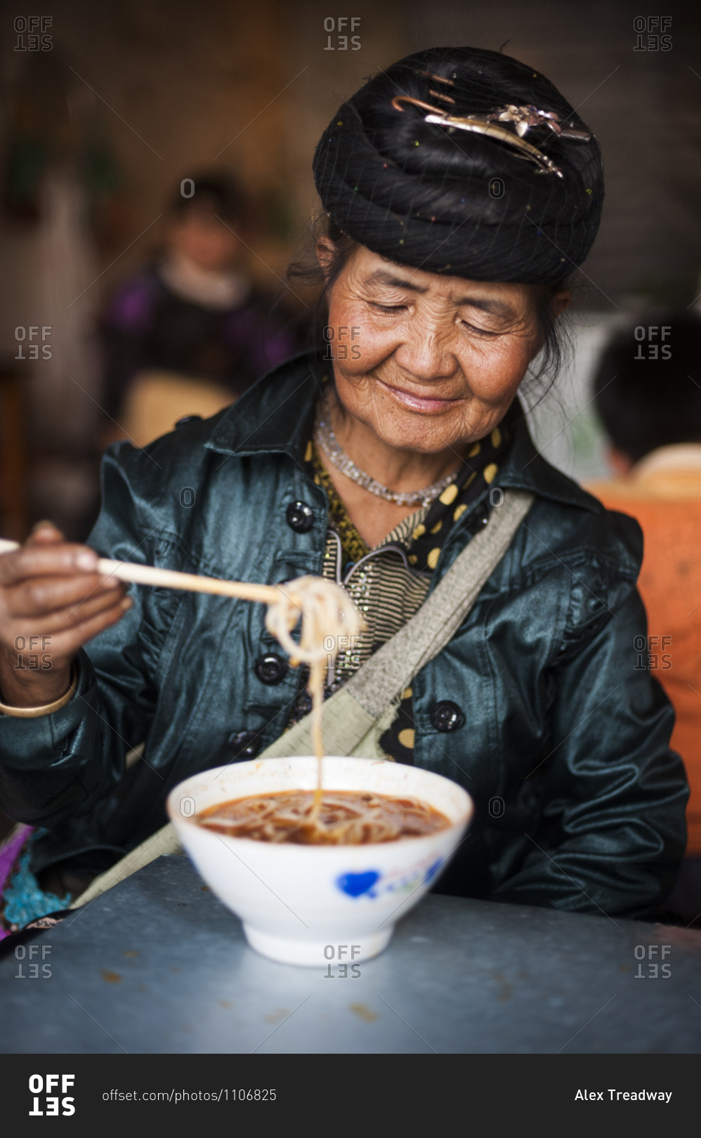 A Miao woman eats a bowl of noodles in the Yunnan province of China