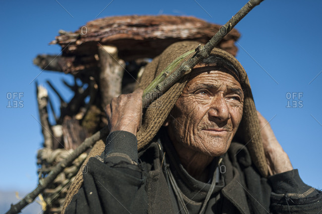 An elderly Gurung man from the Manaslu region in Nepal carries firewood.