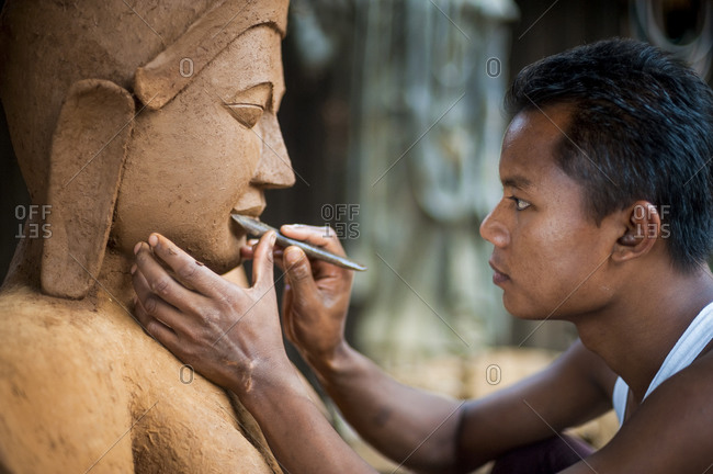 A man sculps a Buddha from clay which will then be bronzed