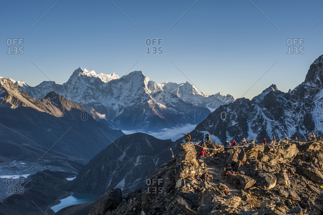 Trekkers stand on the summit of Goyko Ri in the Khumbu region of Nepal looking towards Everest at sunset