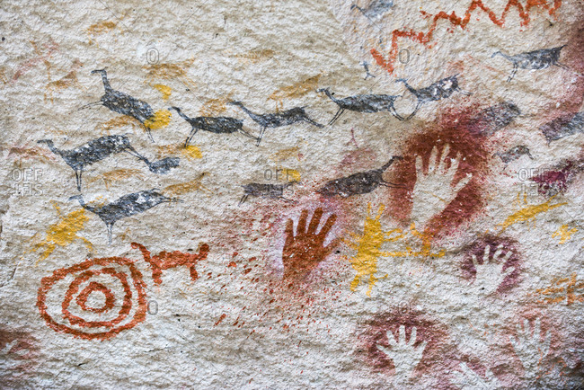An ancient cave painting depiction of leaping Guanacos and hand prints and concentric circles at Cueva de las Manos in Patagonia in Argentina