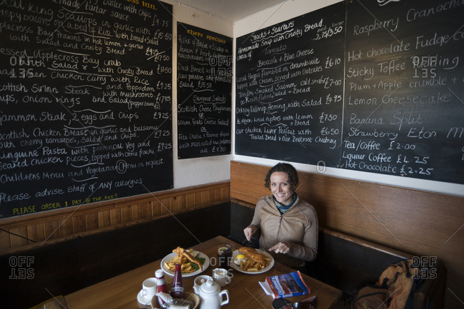 Applecross Bay, Western Highlands, Scotland - May 3, 2011: A woman eats traditional fish and chips in a cafe in Scotland
