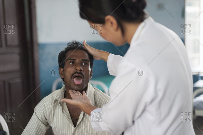 Kapilvastu District, Lumbini Province - October 18, 2011: A doctor looks into a patients mouth in a rural hospital in Nepal