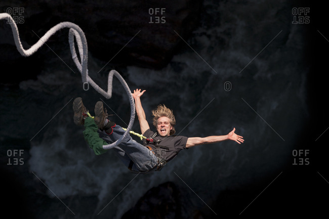 A man smiles for the camera while bouncing back on a bungee jump at The Last Resort in Nepal