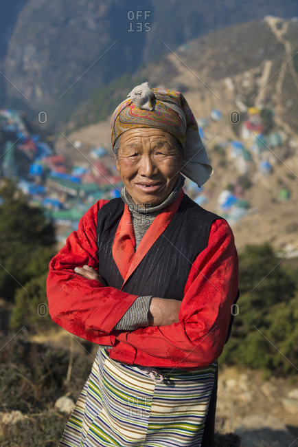 A Tibetan woman wearing traditional dress in the Everest region of Nepal with Namche Bazaar visible in the distance