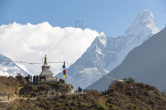Trekkers pass a stupa on their was to Everest Base Camp in the Khumbu region on Nepal with views of Ama Dablam in the distance
