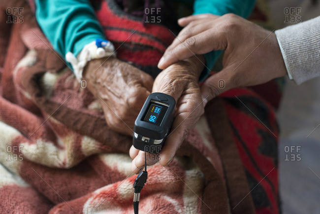 A doctor attaches an oximeter to a patients finger to check oxygen and pulse in a rural hospital in Nepal
