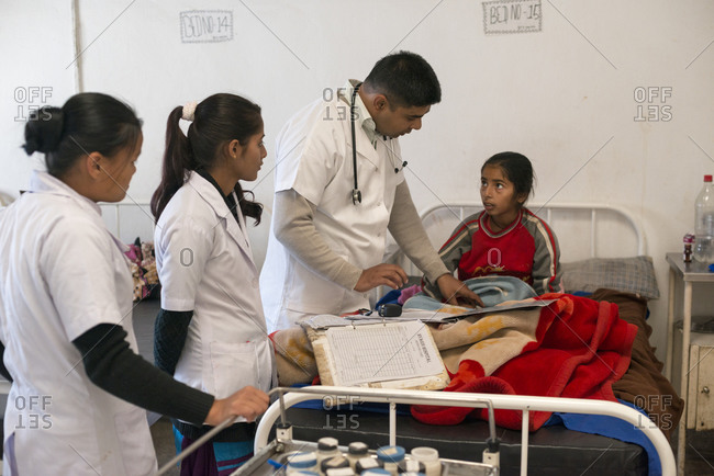 Myagdi, Nepal - November 26, 2013: A doctor examines a little girl in a rural hospital in Nepal while nurses observe