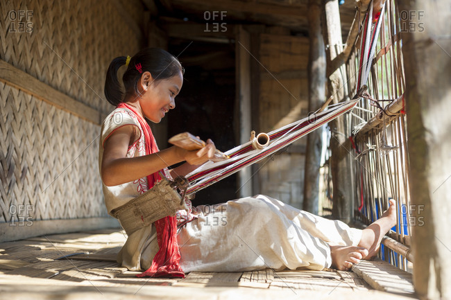 A girl learns the traditional art of weaving on a hand loom