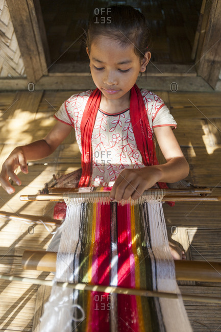 A girl learns the traditional art of weaving on a hand loom