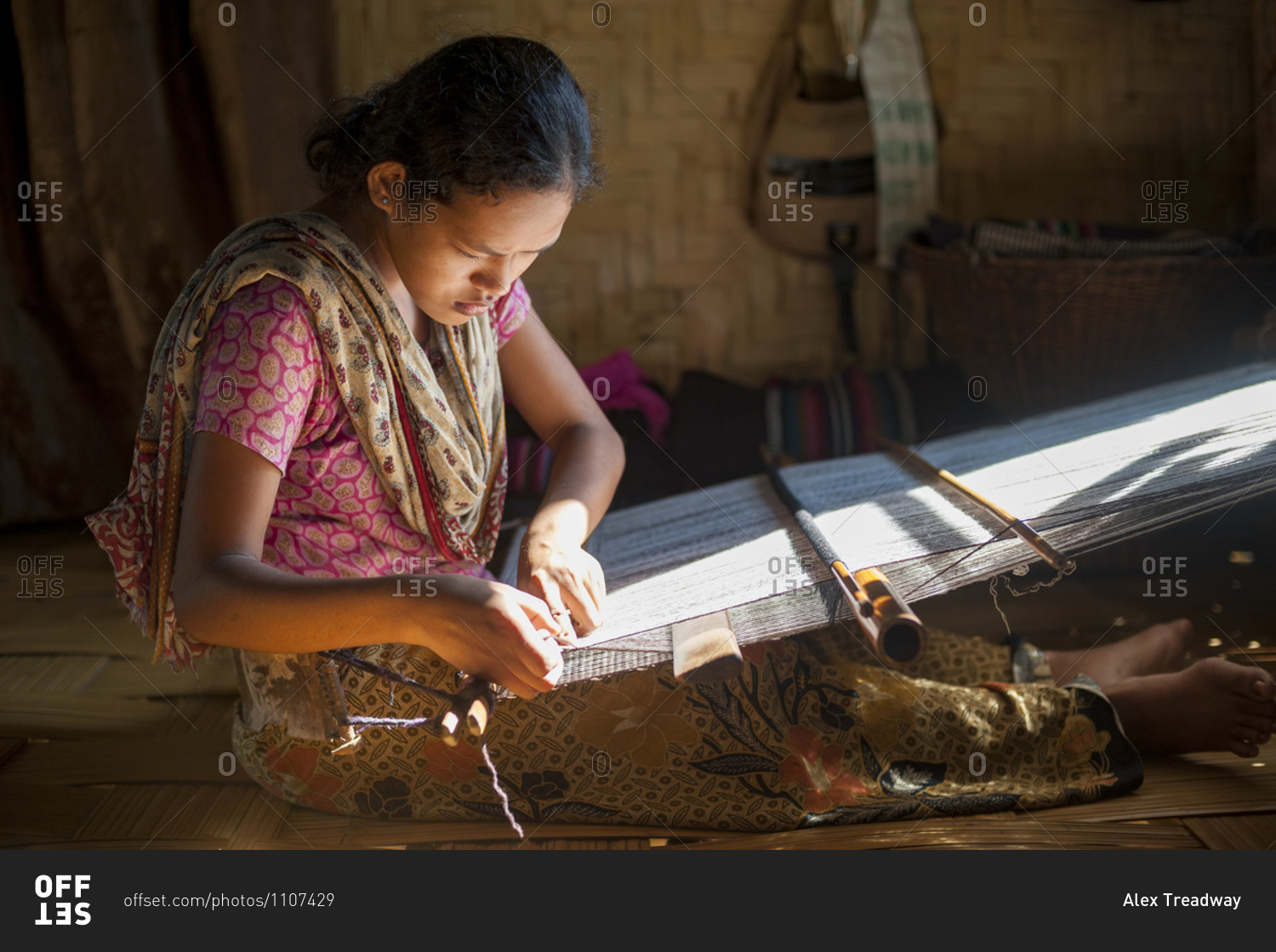 A woman weaves using the traditional method on a hand loom