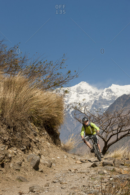 A mountain biker in Nepal with views of Sringi Himal in the distance