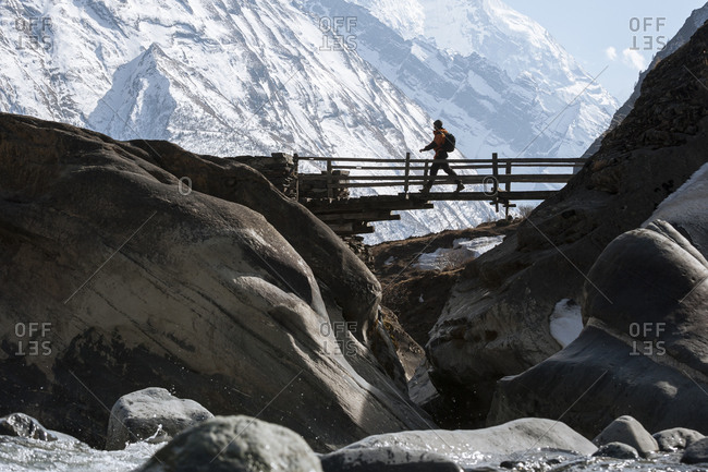 A trekker crosses a wooden bridge in the Tsum valley in Nepal