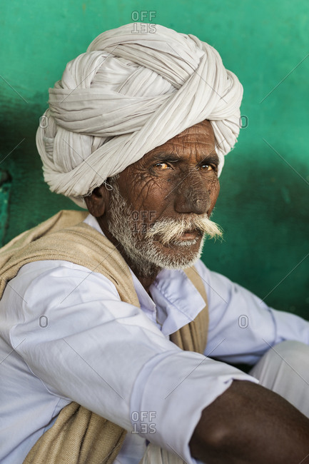 An old Rajasthani farmer with a face weathered from years of sun and hard word enjoys a rest in a small chai shop near Bundi in Rajasthan
