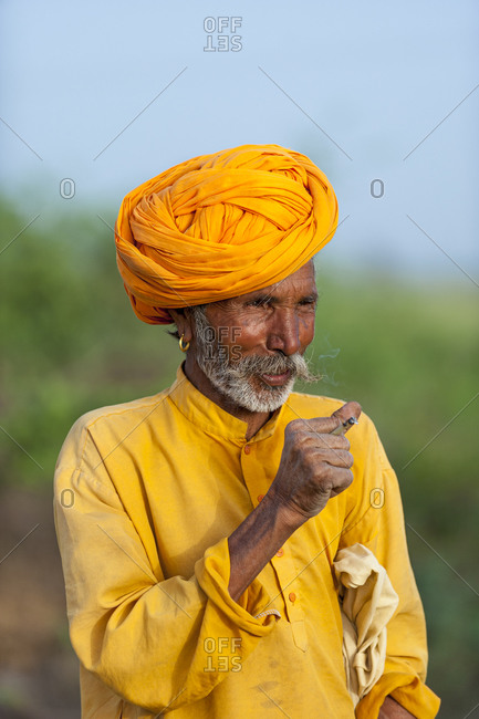 A Rajasthani farmer wearing traditional bright orange clothes and turban