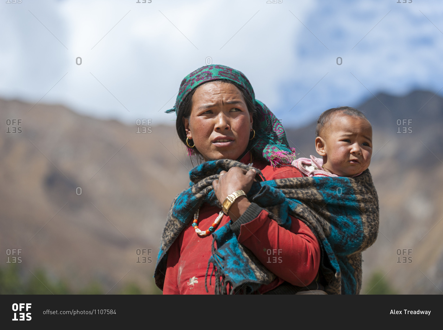 A Tibetan woman carrying her baby in a shawl on her back in Dolpa, a ...